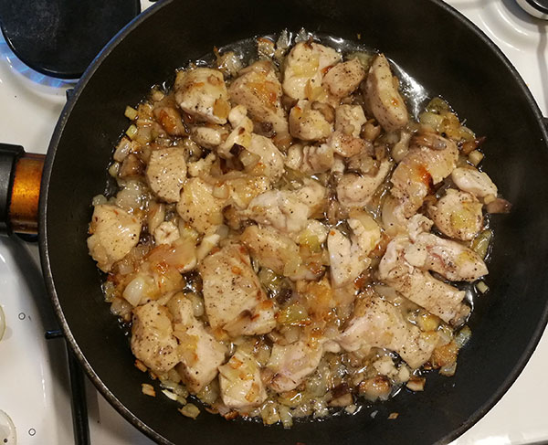 На фото жареный картофель с курицей и грибами в сковороде