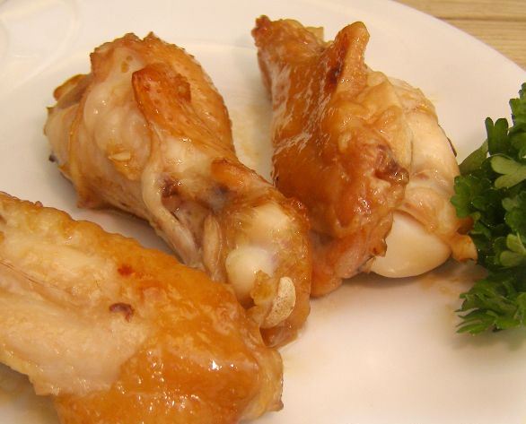 Запечённые в духовке куриные крылышки на тарелке с зеленью