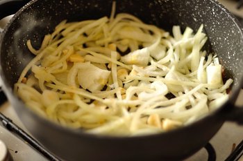 Обжаривание на плите крупнопорезанного лука и чеснока в сковороде