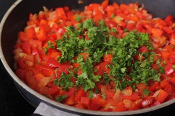 Мелкопорезанная петрушка соль и перец добавляются в тушеную смесь помидоров и болгарского перца
