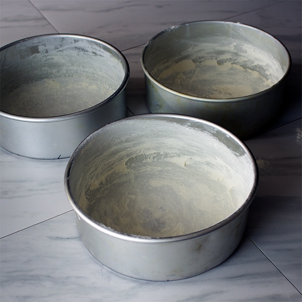 Tracing the bottom of cake pans to cut out parchment circles that will line the bottom of the pans.