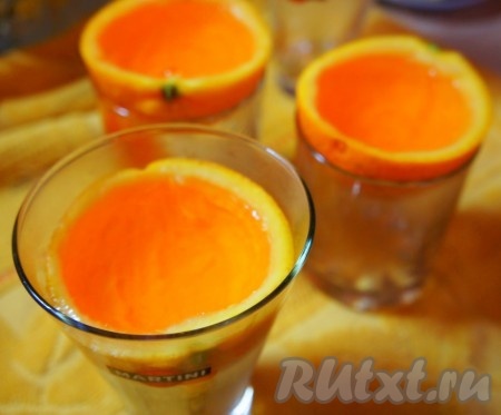 Апельсиновые корки поместить в стаканы или кружки, залить желе. Дать немного остыть и поставить в холодильник до полного затвердевания. Ориентировочно на 2 часа. Всё зависит от производителя желе.
