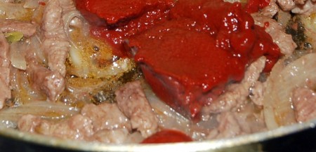 Мясо нарезать небольшими кусочками и обжарить вместе с томатной пастой, все время помешивая, в течение 30 минут.