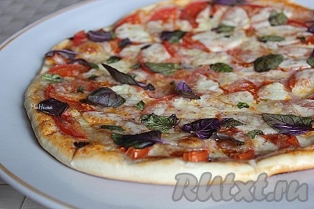 Осталось посыпать пиццу "Маргариту", приготовленную в домашних условиях, листочками базилика.
