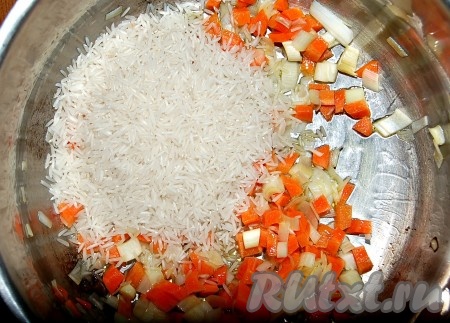 Обжаривать морковь с луком 5 минут, затем добавить в кастрюлю сухой рис.