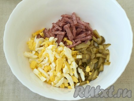 Сварить и очистить яйца, нарезать их соломкой и добавить к колбасе с огурцами.