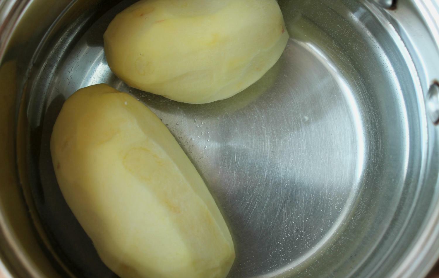 два очищенных картофеля в кастрюле с водой