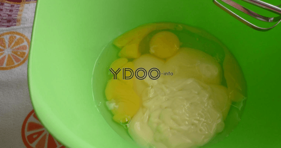 сырые куриные яйца со сгущенкой в глубокой пластиковой миске зеленого цвета