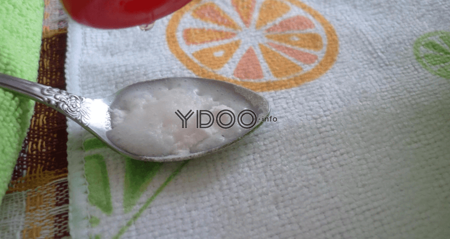 чайная ложка пищевой соды, лежащая на махровом полотенчике с изображение апельсина
