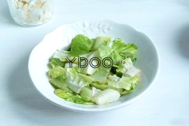 листья салата на дне белой глубокой тарелки на столе