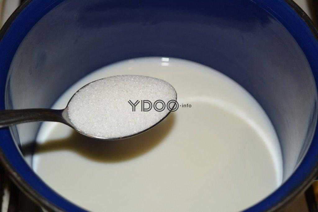 столовая ложка сахара над кастрюлькой с молоком