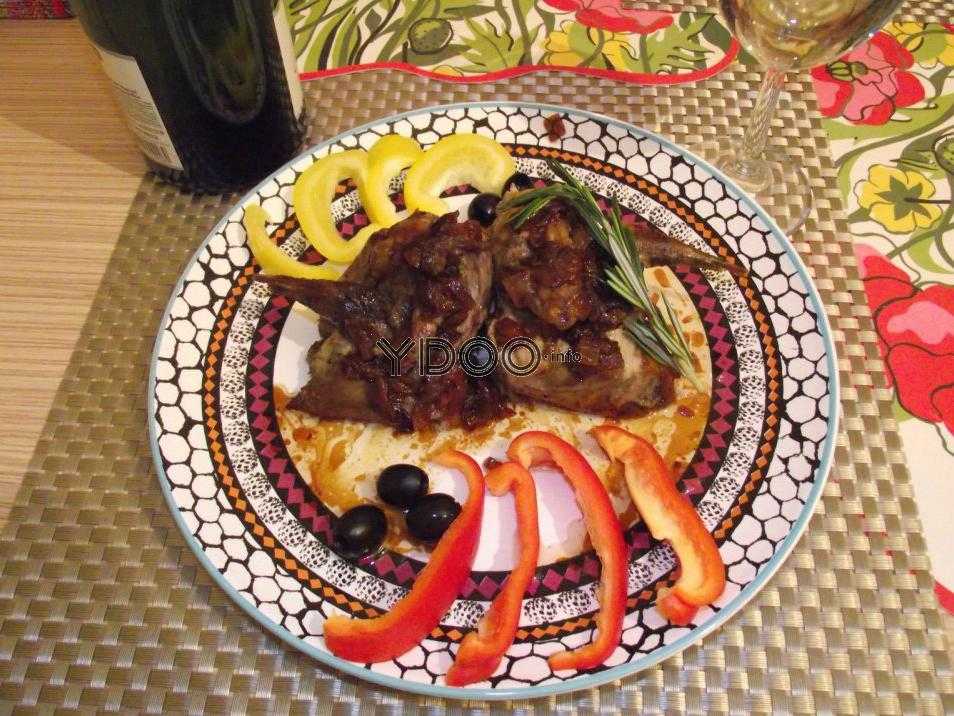 тарелка жареных рябчиков с овощным гарниром на столе, рядом бокал с белым вином и целая бутылка вина