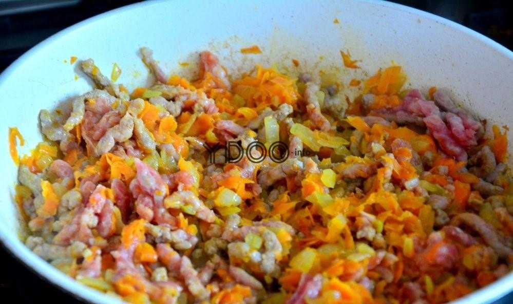 свино-говяжий фарш с луком и морковью жарится в сковородке со сливочным маслом