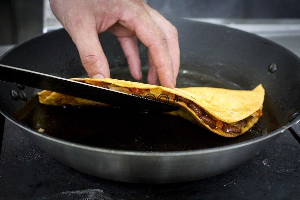 кесадилья с начинкой из овощей обжаривается на сковородке, переворачивается при помощи лопатки и руки на другую сторону