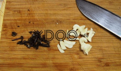 измельченные базилик и чеснок на деревянной доске на столе, рядом лежит большой кухонный нож