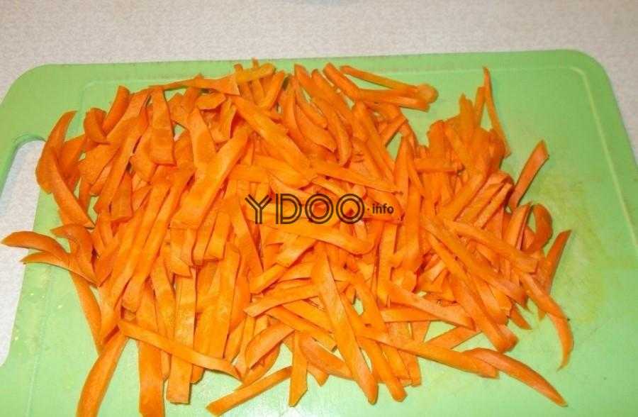 морковь, нарезанная полосками, лежит на зеленой доске