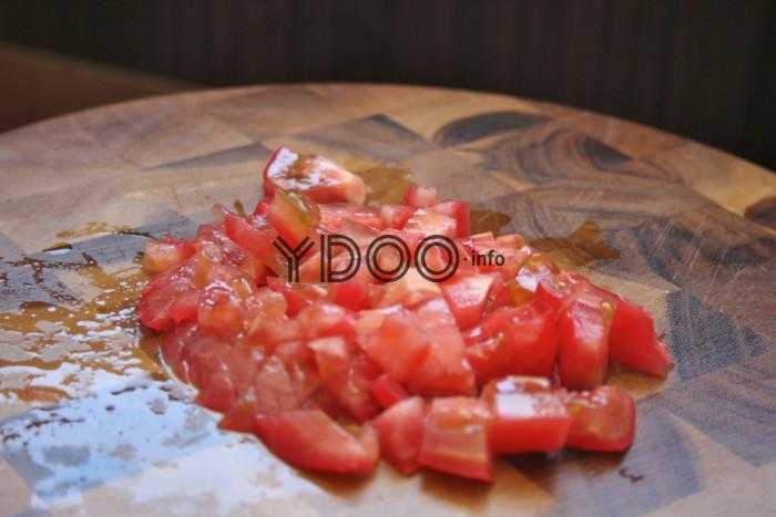 помидор, нарезанный кубиками, лежит на деревянной доске