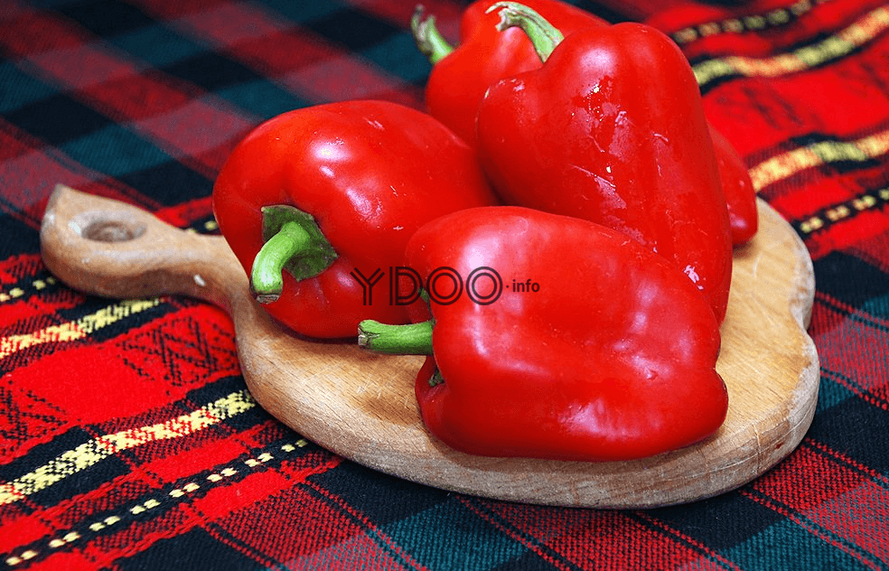 на деревянной доске лежат три красных болгарских перца