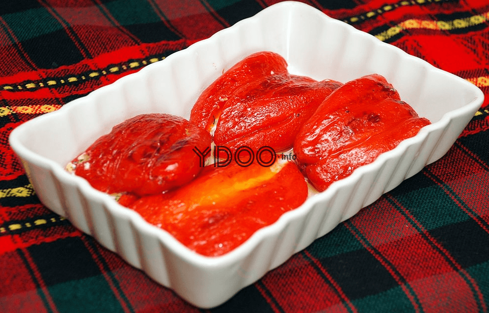 в прямоугольной жаропрочной форме лежат четыре красных болгарских перца с начинкой из сыра