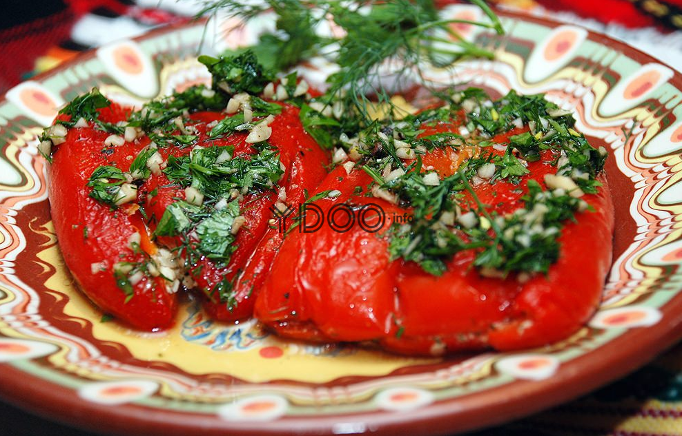 на тарелке лежат три красных болгарских перца, политые маринадом из измельченного чеснока и зелени