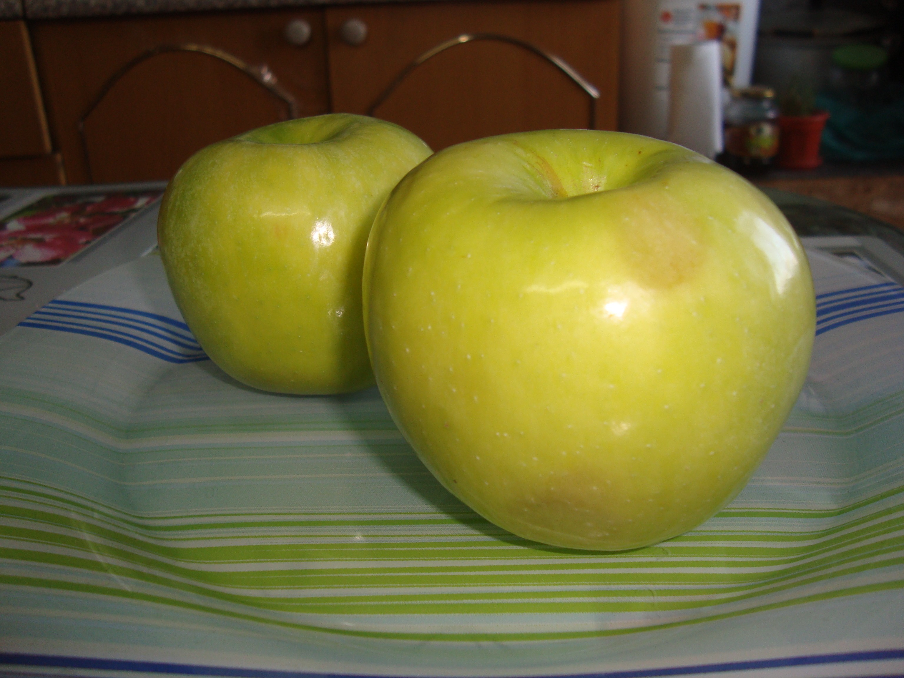 два зеленых яблока на тарелке на столе