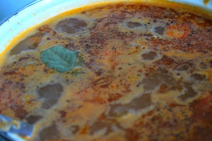 кипящий томатный суп в белой кастрюле