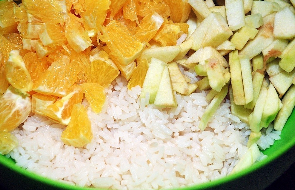 вареный рис, нарезанные яблоки и апельсины в зеленой миске