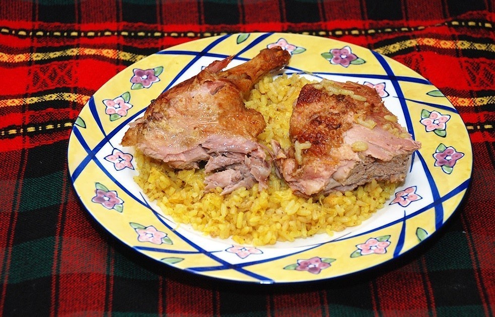 испеченные кусочки мяса утки с вареным рисом на плоской тарелке на столе, покрытом тканью